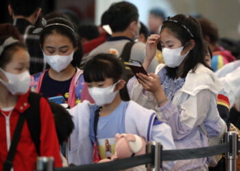 Dzieci w maskach ochronnych stoją w kolejce przy stanowisku odprawy na lotnisku Changi w Singapurze. Linie lotnicze "Scoot" odwołały swój codzienny lot do Wuhan w Chinach po tym, jak miasto zostało zamknięte przez chińskie władze po wybuchu epidemii koronawirusa. Fot. PAP/EPA/WALLACE WOON