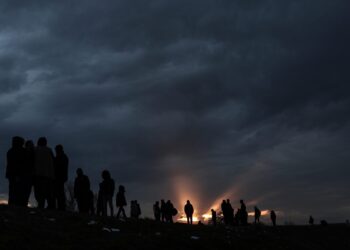 Grupa migrantów czeka nad rzeką Tunca, próbując przeprawić się, by dotrzeć do Grecji podczas zachodu słońca w centrum miasta Edirne (Turcja), 4 marca 2020 r. Tysiące uchodźców i migrantów gromadzą się po tureckiej stronie granicy z Grecja z zamiarem wkroczenia do Unii Europejskiej po decyzji rządu tureckiego o rozluźnieniu kontroli przepływów migrantów po śmierci 33 żołnierzy tureckich zabitych w zamachu w Idlib w Syrii w dniu 27 lutego 2020 r. Fot. PAP/EPA/SEDAT SUNA