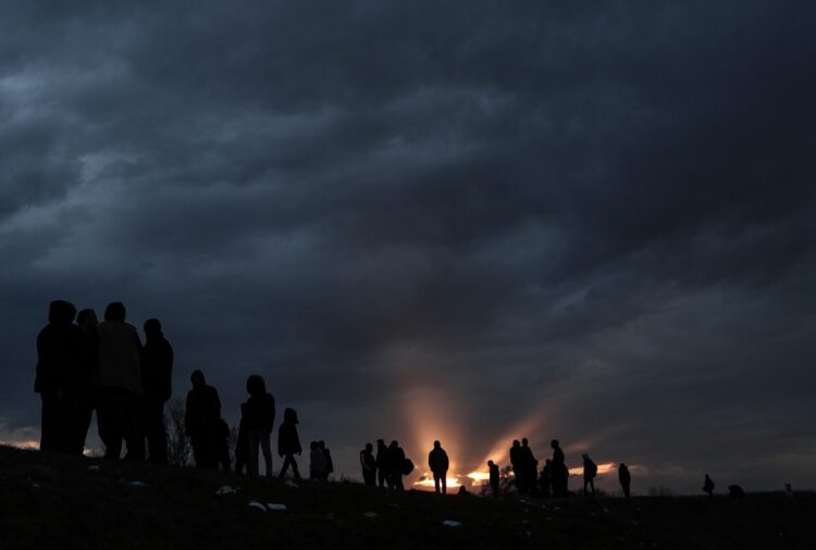 Grupa migrantów czeka nad rzeką Tunca, próbując przeprawić się, by dotrzeć do Grecji podczas zachodu słońca w centrum miasta Edirne (Turcja), 4 marca 2020 r. Tysiące uchodźców i migrantów gromadzą się po tureckiej stronie granicy z Grecja z zamiarem wkroczenia do Unii Europejskiej po decyzji rządu tureckiego o rozluźnieniu kontroli przepływów migrantów po śmierci 33 żołnierzy tureckich zabitych w zamachu w Idlib w Syrii w dniu 27 lutego 2020 r. Fot. PAP/EPA/SEDAT SUNA