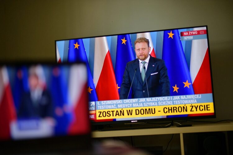 Minister zdrowia Łukasz Szumowski (na ekranie telewizora) podczas konferencji prasowej, 4 bm. odbywającej się bez stacjonarnego udziału mediów.
