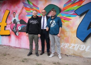 Od lewej: Artur Marciniszyn, burmistrz Iłowej Paweł Lichtański i Łukasz Gierlak na tle jednego z murali. Fot.  z arch. Artura Marciniszyna