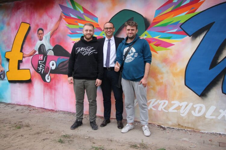 Od lewej: Artur Marciniszyn, burmistrz Iłowej Paweł Lichtański i Łukasz Gierlak na tle jednego z murali. Fot.  z arch. Artura Marciniszyna