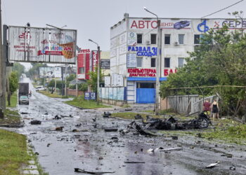 Mieszkańcy patrzą na uszkodzony samochód, w którym mężczyzna i jego syn zostali zabici po uderzeniu rosyjskiej rakiety w Charkowie, 11 lipca 2022 r. Co najmniej sześć osób zginęło, a 31 zostało rannych w rejonie Charkowa. Fot. PAP/EPA KOZLOV SERGEY