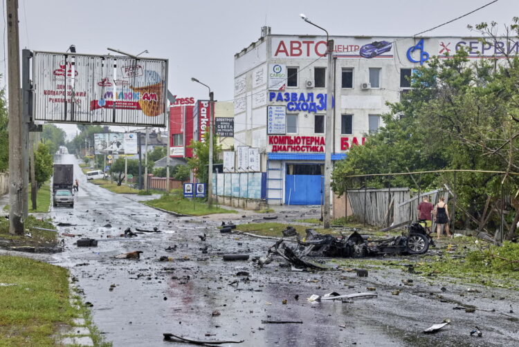 Mieszkańcy patrzą na uszkodzony samochód, w którym mężczyzna i jego syn zostali zabici po uderzeniu rosyjskiej rakiety w Charkowie, 11 lipca 2022 r. Co najmniej sześć osób zginęło, a 31 zostało rannych w rejonie Charkowa. Fot. PAP/EPA KOZLOV SERGEY