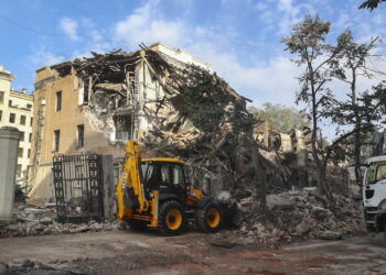 Robotnicy komunalni sprzątają gruz uszkodzonego budynku po ostrzale w centrum Charkowa, 29 sierpnia 2022 r. Charków i okolice są celem ciężkich ostrzałów od lutego 2022 r., kiedy to wojska rosyjskie wkroczyły na Ukrainę. Fot. PAP/EPA/SERGEY KOZLOV