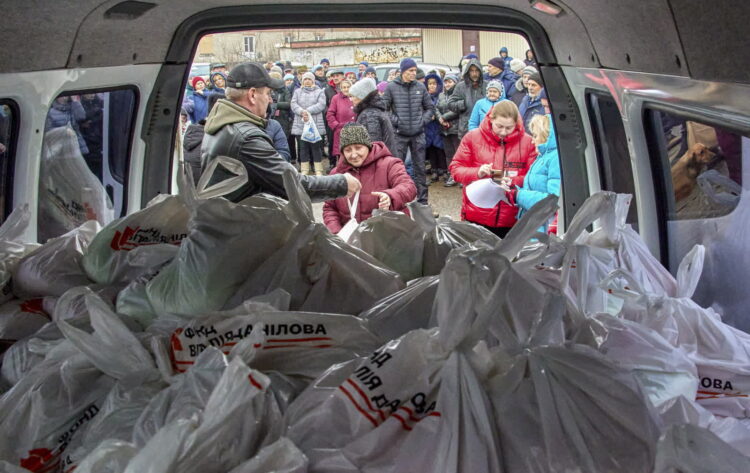 Wolontariusze udzielają pomocy humanitarnej mieszkańcom przedmieść Charkowa na Ukrainie, 16 grudnia 2022 r. Fala rosyjskich ataków rakietowych wymierzona została w stolicę Ukrainy, Kijów, i inne części kraju. Fot. PAP/EPA/SERGEY KOZLOV