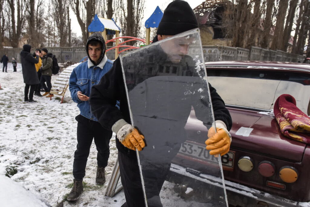 Serhij, mieszkaniec Kijowa niesie nową szybę do okna, uszkodzonego w wyniku eksplozji, w pobliżu budynku zniszczonego przez rosyjski dron, Kijów, Ukraina, 14 grudnia 2022 r. Fot. PAP/EPA/OLEG PETRASYUK