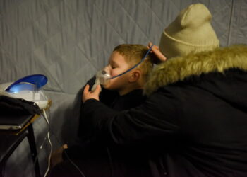 Olga i jej syn Sviatoslv podłączają inhalator do generatora prądu w punkcie zorganizowanym przez państwowe pogotowie ratunkowe, podczas przerwy w dostawie prądu w Kijowie na Ukrainie, 16 grudnia 2022 r. Fot. PAP/EPA/OLEG PETRASYUK