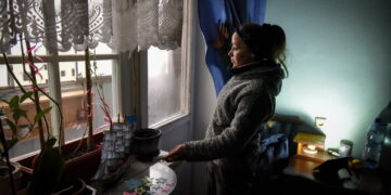 Tetiana pokazuje działanie lampy ładującej się z panelu słonecznego w swoim mieszkaniu w zniszczonym bloku mieszkalnym w Horence koło Kijowa, Ukraina, 03 grudnia 2022 r. Fot. PAP/EPA/OLEG PETRASYUK