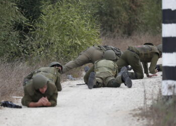 Izraelscy żołnierze ukrywają się podczas ataku rakietowego w pobliżu granicy ze Strefą Gazy, niedaleko Sderot, południowy Izrael. Fot. PAP/EPA/ATEF SAFADI
