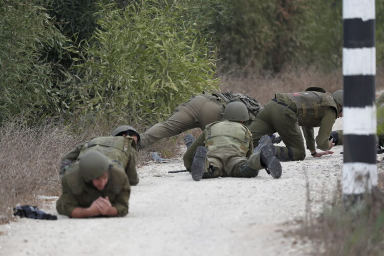 Izraelscy żołnierze ukrywają się podczas ataku rakietowego w pobliżu granicy ze Strefą Gazy, niedaleko Sderot, południowy Izrael. Fot. PAP/EPA/ATEF SAFADI