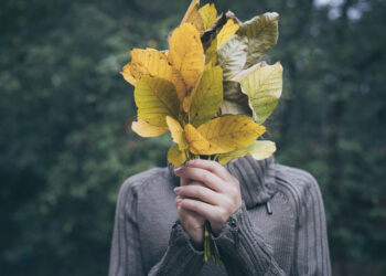 Portrait of a sad teenage girl with  leaves in her hands.