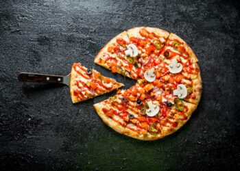 Sliced Mexican pizza. On black rustic background