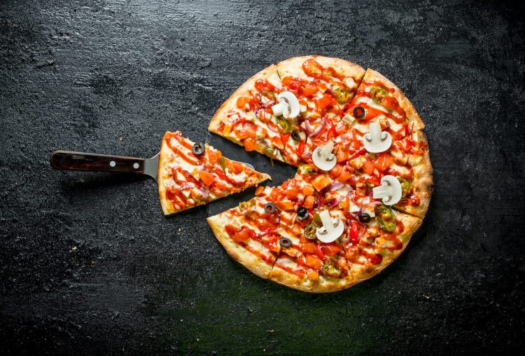 Sliced Mexican pizza. On black rustic background