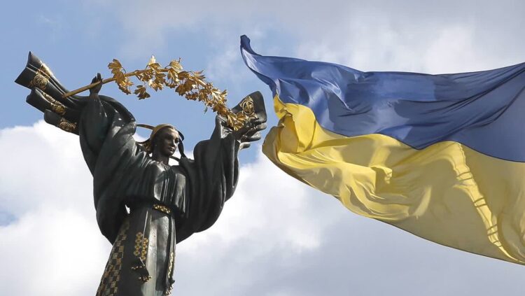 Ukraińska flaga obok pomnika na Placu Niepodległości w centrum Kijowa Fot. PAP/EPA/SERGEY DOLZHENKO SERGEY DOLZHENKO