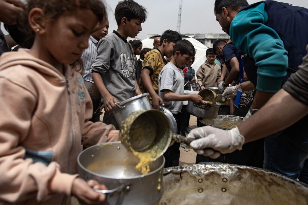 Palestyńskie dzieci otrzymujące darmowe posiłki w północnej części Strefy Gazy (PAP/EPA/HAITHAM IMAD)