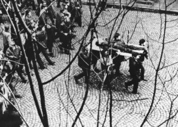 Gdynia 17.12.1970. Demonstranci niosą na drzwiach zwłoki Zbigniewa Godlewskiego. Zbigniew Godlewski zginął w okolicy przystanku Szybkiej Kolei Miejskiej Gdynia Stocznia, przeszyty serią z karabinu maszynowego. Fot. PAP/Edmund Pepliński