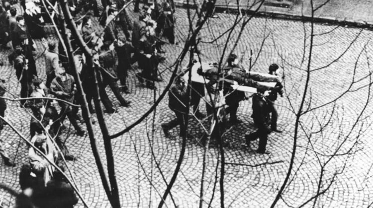 Gdynia 17.12.1970. Demonstranci niosą na drzwiach zwłoki Zbigniewa Godlewskiego. Zbigniew Godlewski zginął w okolicy przystanku Szybkiej Kolei Miejskiej Gdynia Stocznia, przeszyty serią z karabinu maszynowego. Fot. PAP/Edmund Pepliński