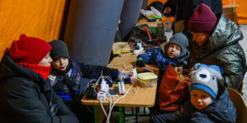 Mieszkańcy Kijowa gromadzą się w ogrzewanym namiocie, w którym można także doładować urządzenia elektroniczne. Fot. PAP/Vladyslav Musiienko