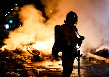 Francuski strażak interweniuje przy płonącej barykadzie ulicznej w Paryżu, podczas starcia między oddziałami prewencji a demonstrantami. Fot. PAP/EPA/MOHAMMED BADRA