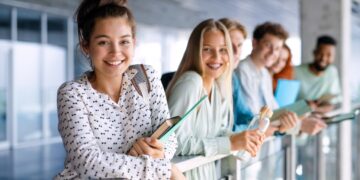 Group of university students standing and looking at camera indoors, back to school concept.